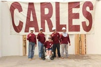 a group of people standing in front of a sign that says carles