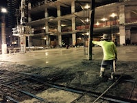 a man is standing on a concrete floor at night