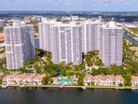 an aerial view of a group of high rise buildings near a body of water